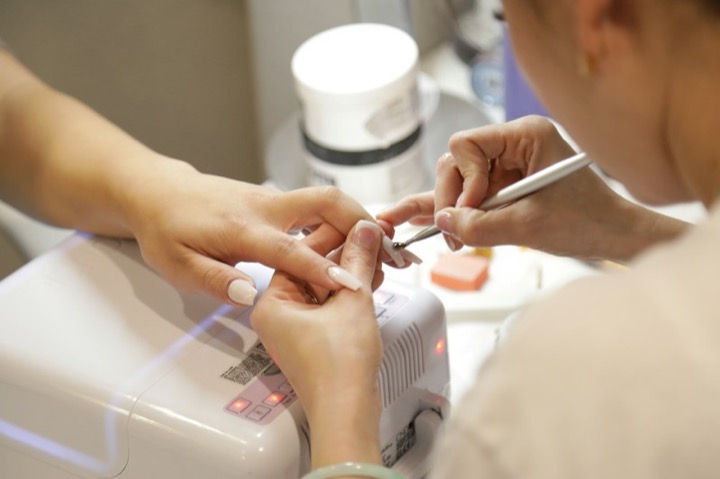 Manicurista trabajando las uñas de una clienta